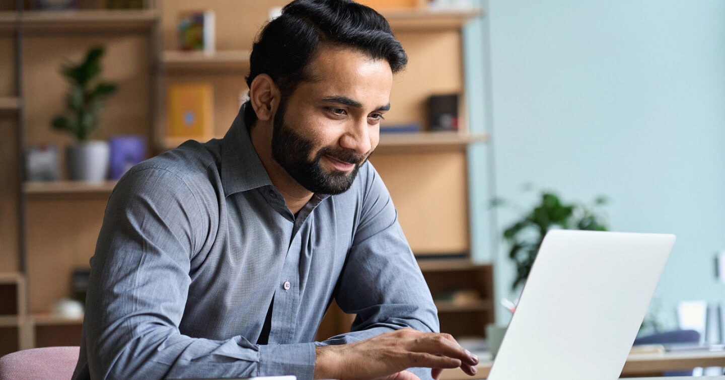 Man sitting at desk working on his laptop.