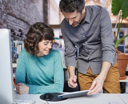 Male pointing to a tablet, while his female coworker looks at the tablet as well.