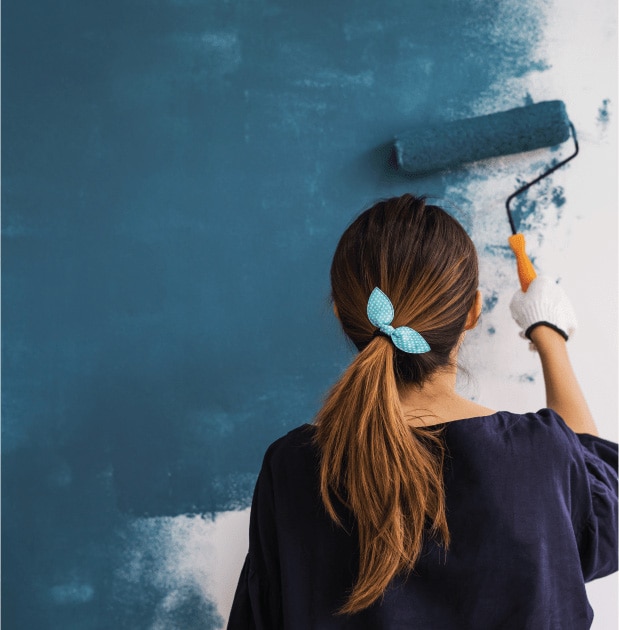 Female store associate painting a wall blue.