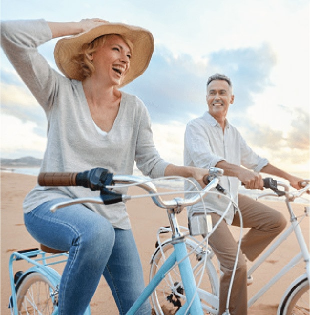 Woman and man riding bicycles on the beach.