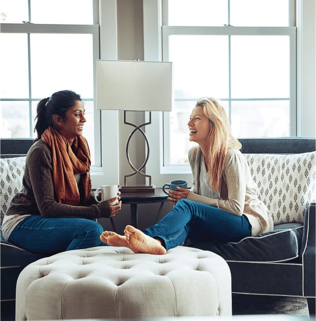 Two ladies sitting, talking and drinking beverages.