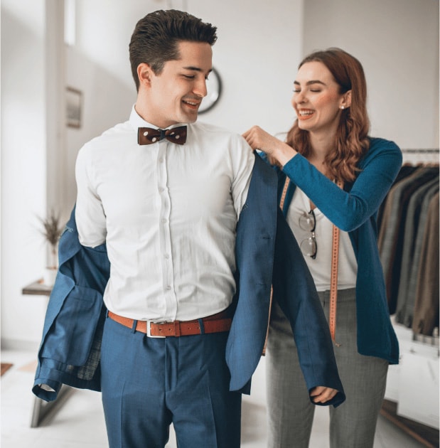 Female tailor fitting young man in bow tie.