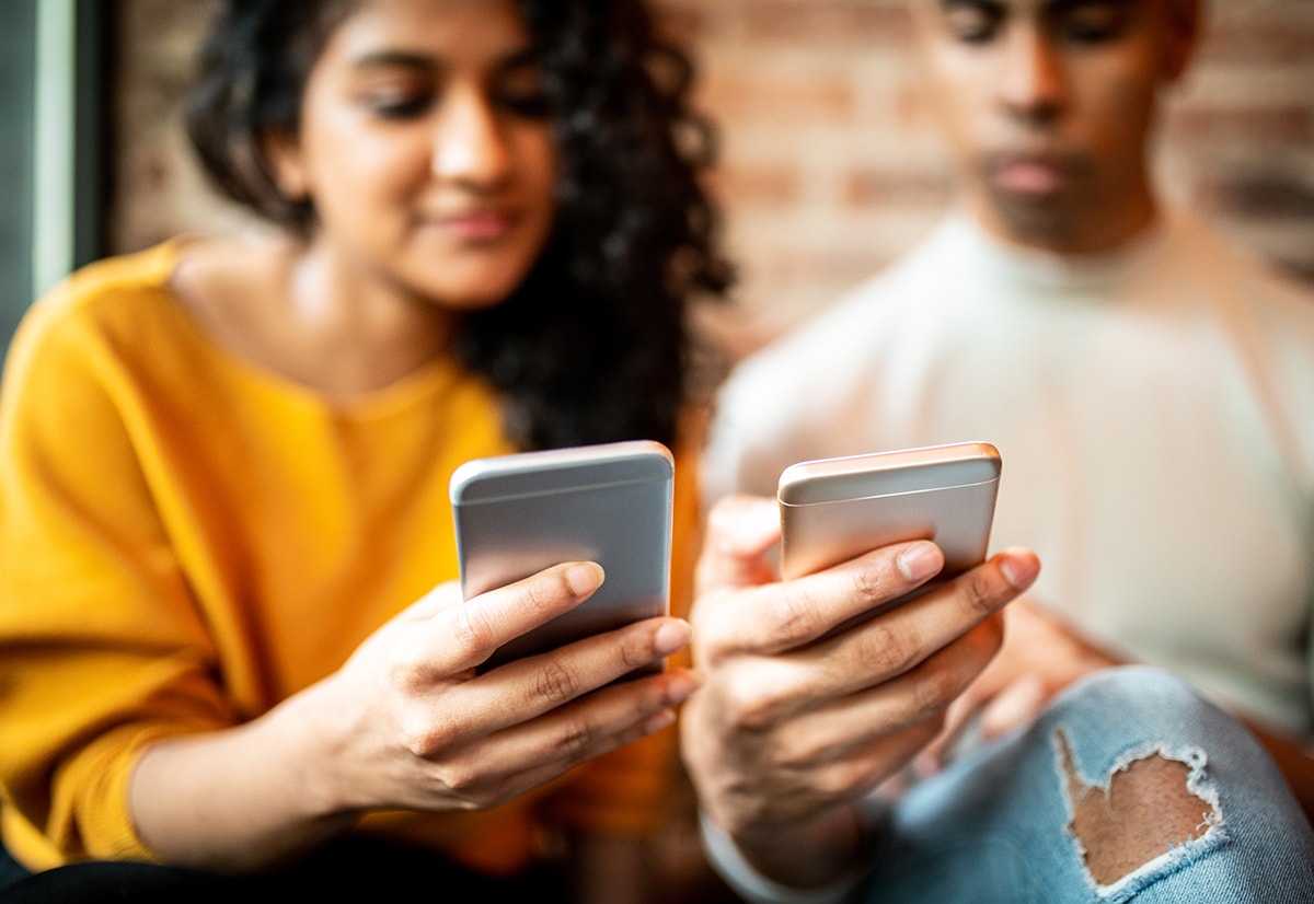 A young man and woman using their smartphones for social media